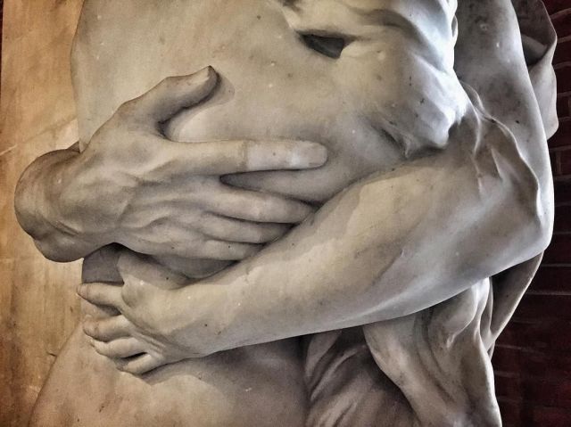 a close up of a statue with hands on it's face and arms wrapped around each other