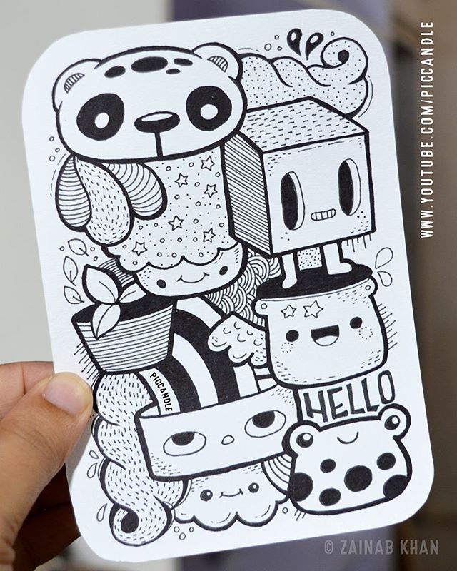 a hand holding up a black and white sticker with cartoon animals on it's face