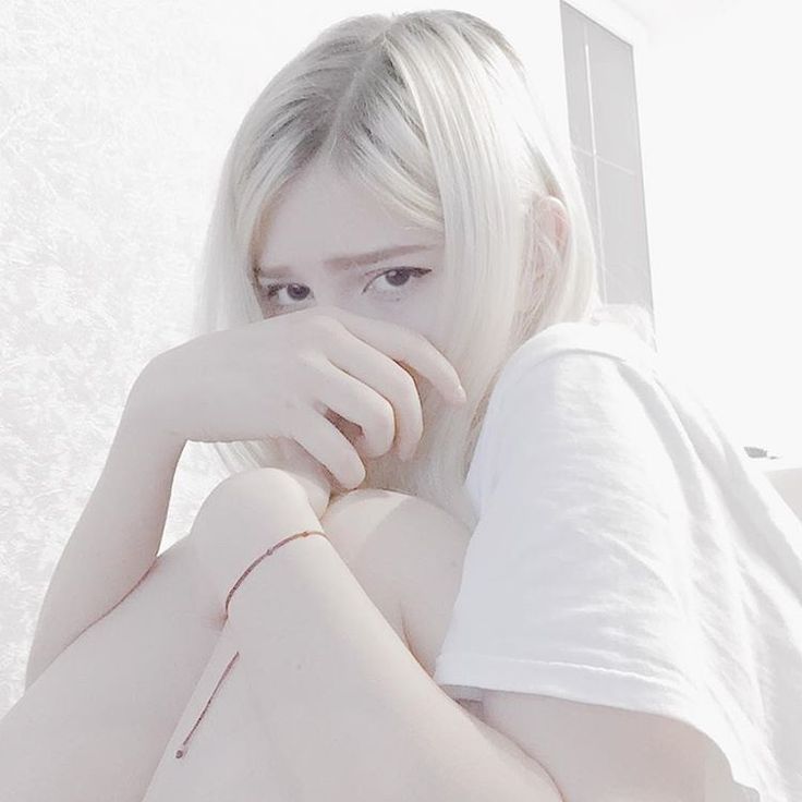 a woman with white hair is posing for the camera, her hand on her face