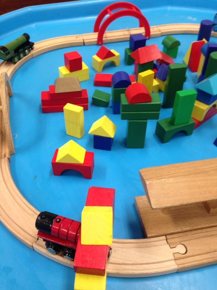 a child's toy train set with wooden blocks and toys on the tracks in a blue tray