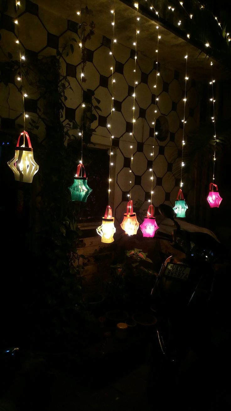 colorful lights hanging from the ceiling in a room with black and white tiles on the wall