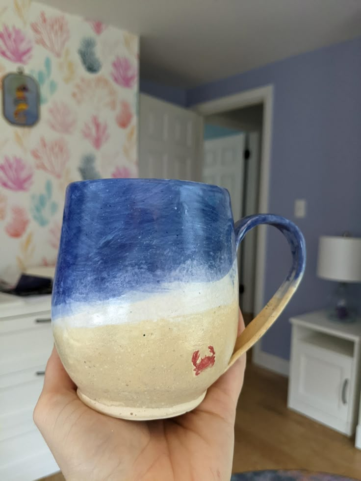 a hand holding a blue and white coffee cup