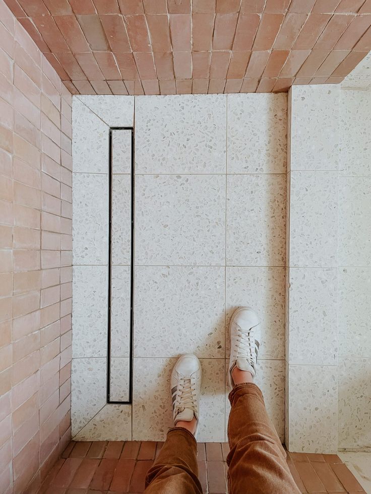 someone's feet in the corner of a room with brick walls and flooring