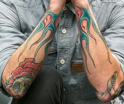 a man with tattoos on his arms sitting down