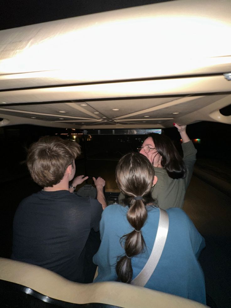 three people sitting under a car looking at something