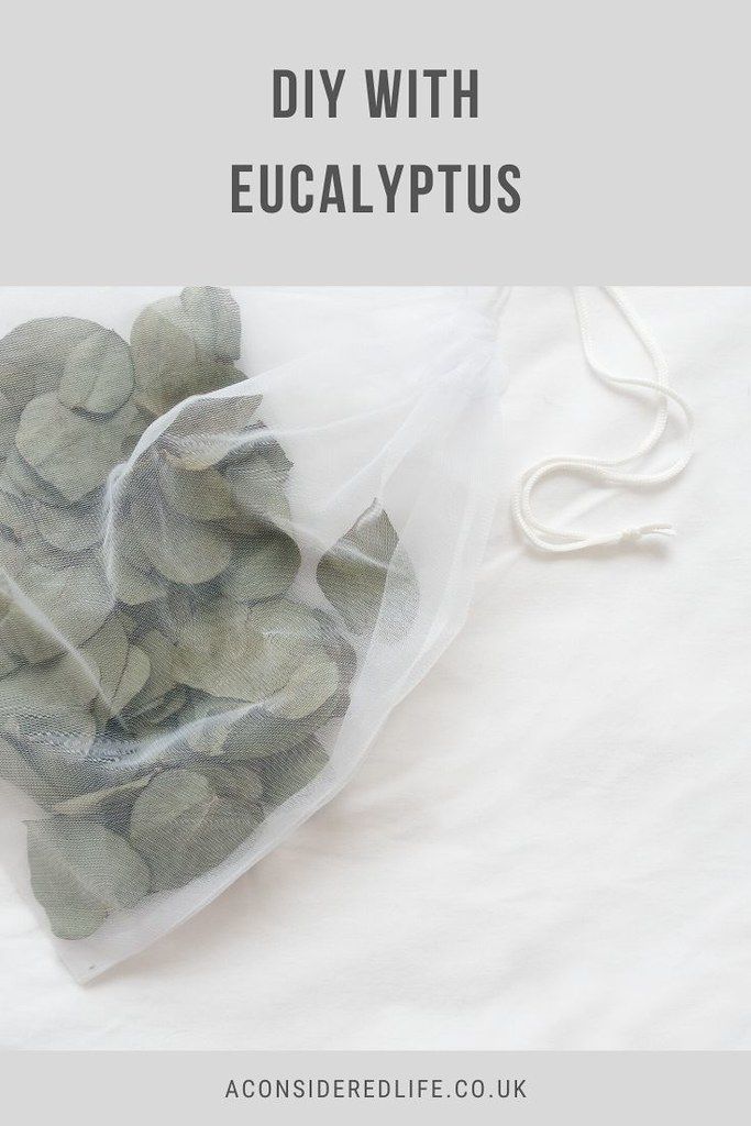 a bag filled with green leaves sitting on top of a white sheeted bed next to a string