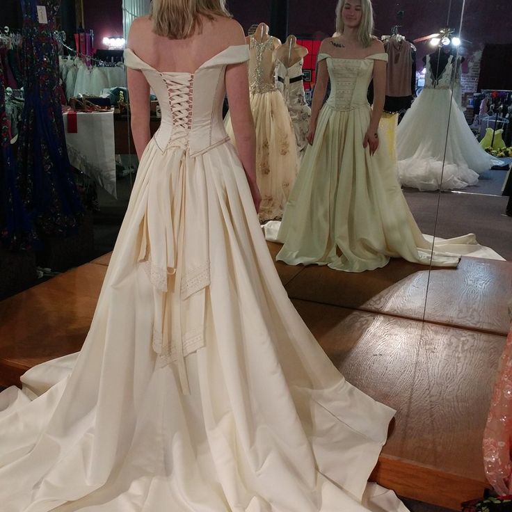 a woman in a wedding dress looking at herself in the mirror