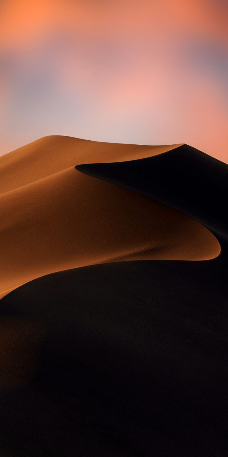 an orange and pink sky over sand dunes