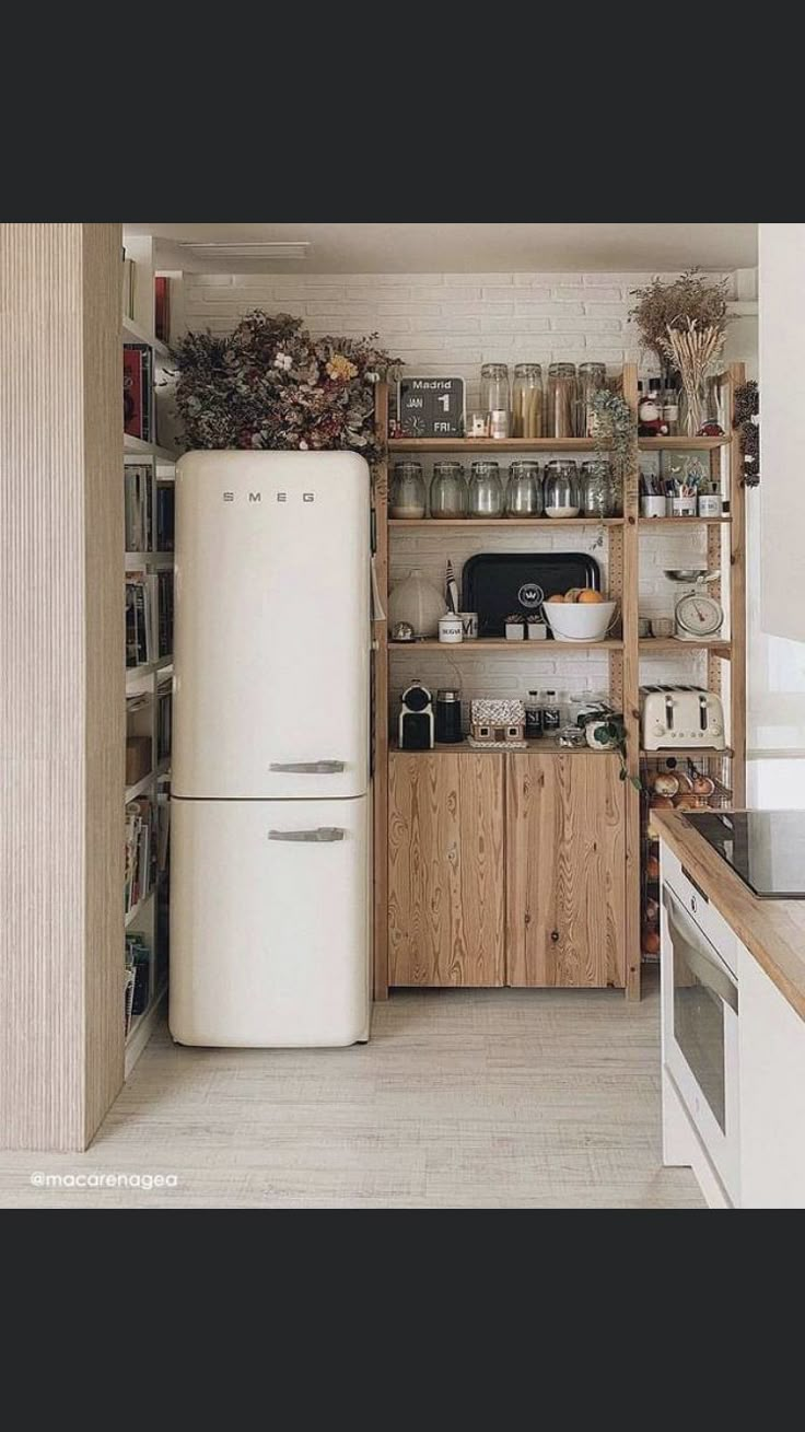 an old fashioned refrigerator is in the middle of a kitchen with wooden shelves and shelving