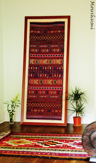 a large colorful rug sitting on top of a wooden floor next to a potted plant