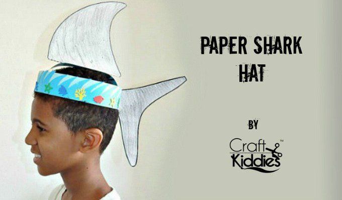 a young boy wearing a paper shark hat with fish on it's head and the words paper shark hat written below