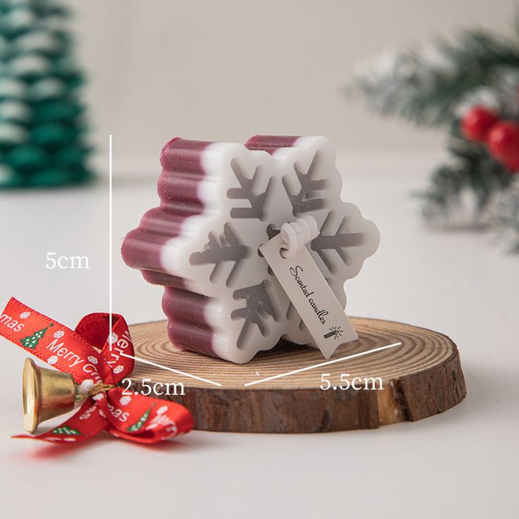 a snowflake shaped candle is on a wooden stand with a red ribbon around it