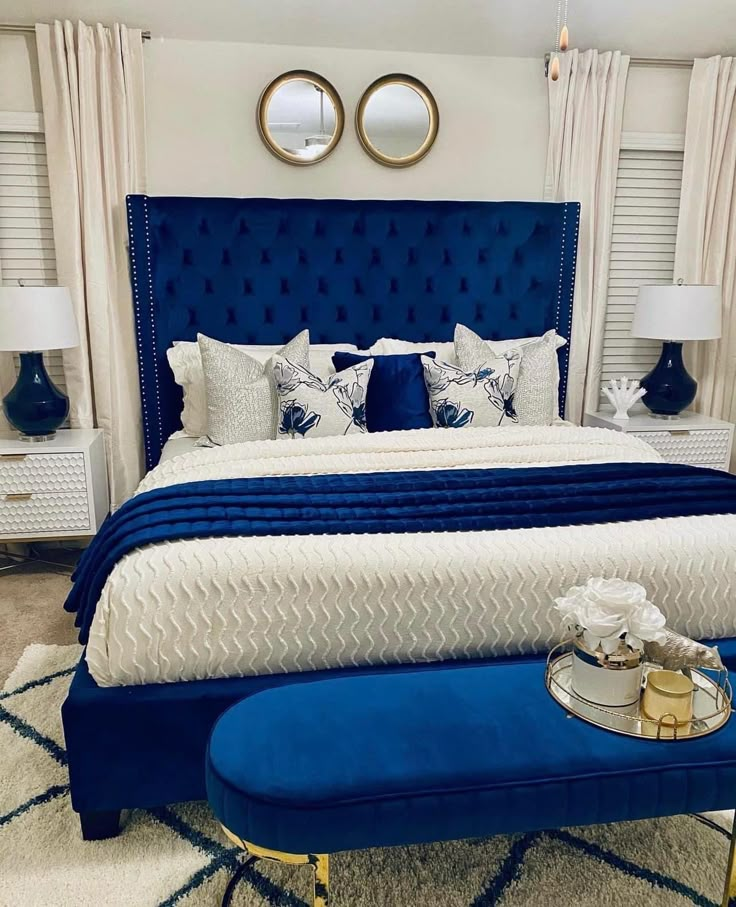 a blue and white bedroom with two round mirrors above the bed