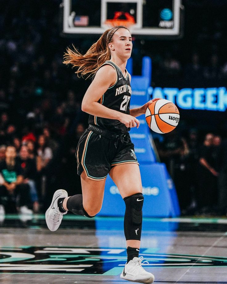 a female basketball player is running with the ball in her hand and people are watching