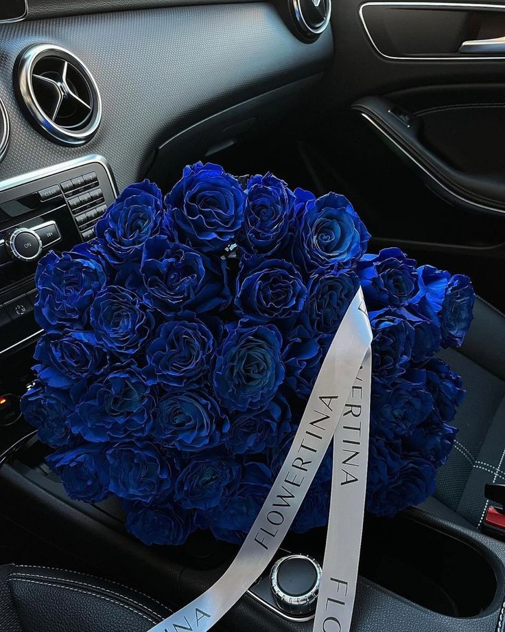 a bouquet of blue roses sitting on the dashboard of a car