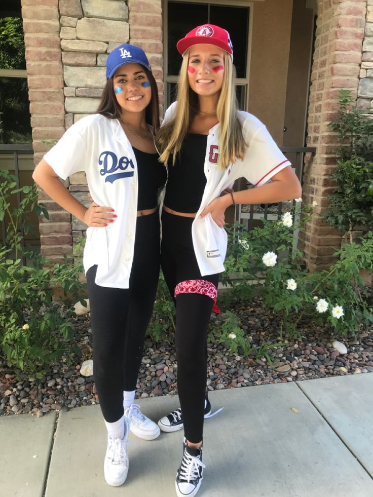 two girls are posing in front of a house with their faces painted like baseball players