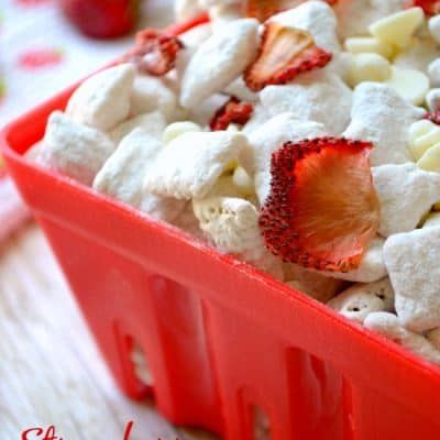 strawberry shortcake muddy buddies in a red plastic container with strawberries on the side