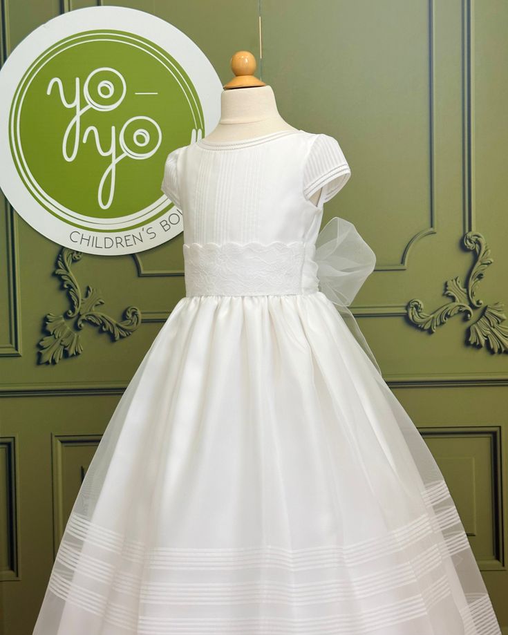 A traditional and classical first communion gown for girls, made with a lightweight white organza. It has beautiful pleats throughout the body and skirt. The flower appliqué is removable. It has buttons on the back for closure. True to size Dry clean 100% polyester Made in Spain Does not include crinoline Final Sale, no exchanges nor returns will be accepted Dress For Teenage Girl, Holy Communion Dresses, First Communion Dress, Spanish Fashion, First Communion Dresses, Gowns For Girls, Communion Dresses, Girl A, First Holy Communion