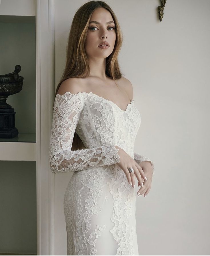 a woman in a white dress leaning against a wall