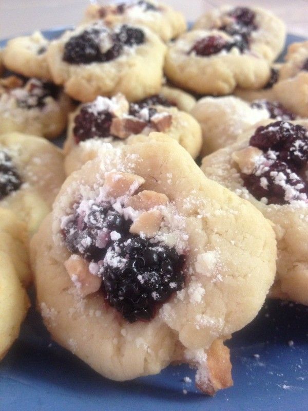 cookies with blueberries and powdered sugar are on a plate, ready to be eaten