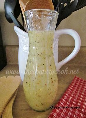 a pitcher filled with liquid sitting on top of a wooden table next to utensils