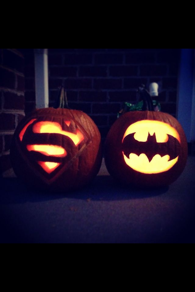 two pumpkins carved to look like batman and superman logos