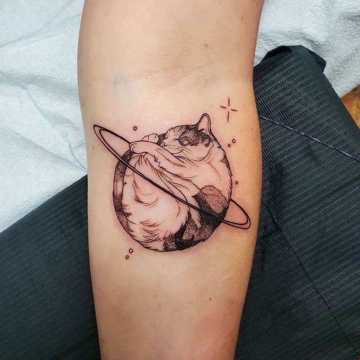 a black and white cat with saturn tattoo on the leg