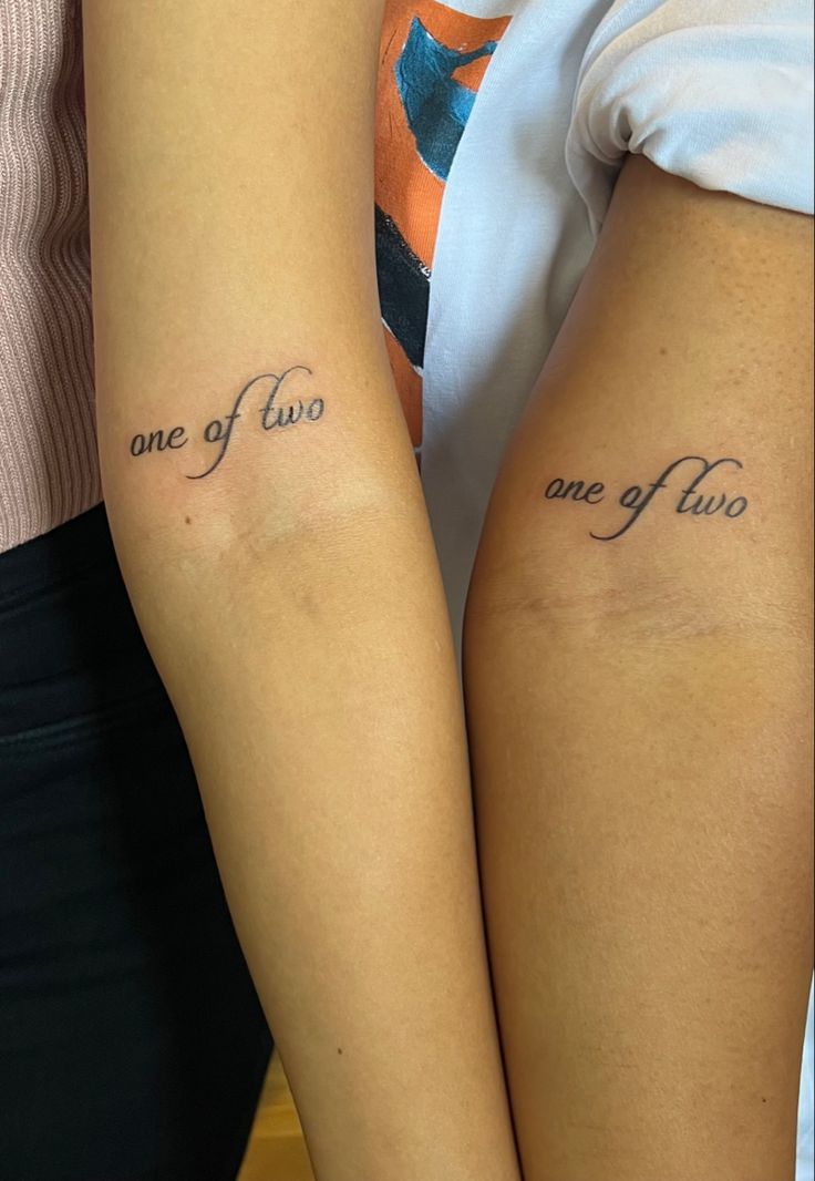 two people with matching tattoos on their arms that say one of two and one of two