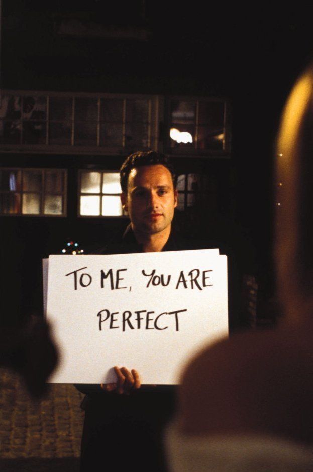 a man holding a sign that says to me, you are perfect in front of him