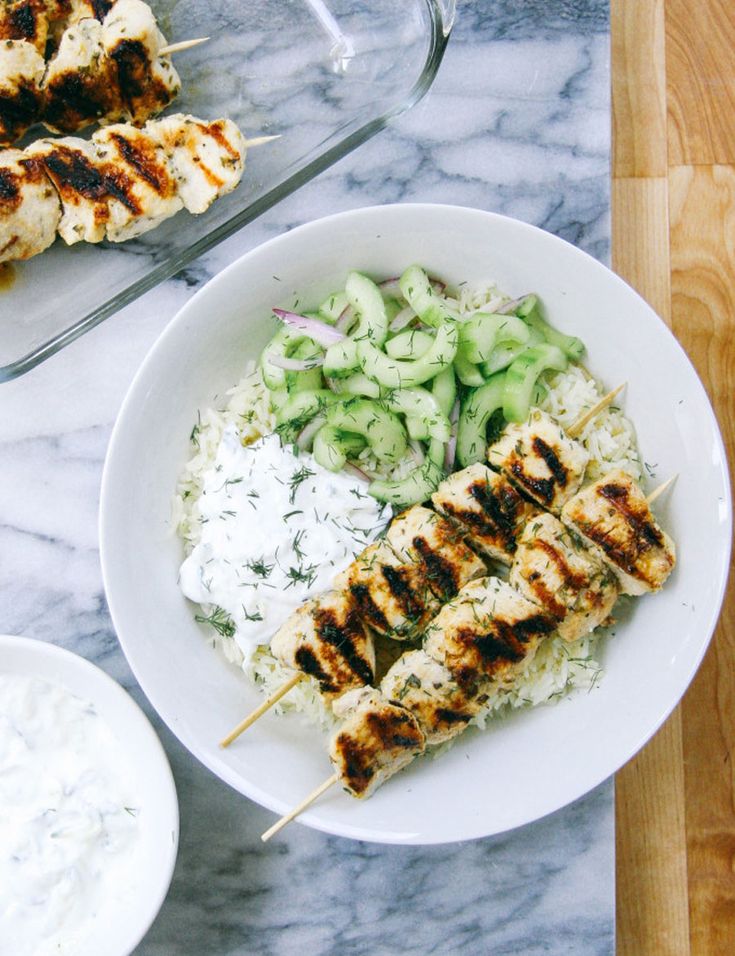 chicken skewers with cucumber salad and ranch dressing on a marble table