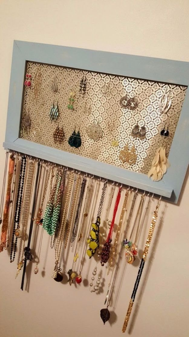 a blue frame with many necklaces hanging from it's sides on a wall