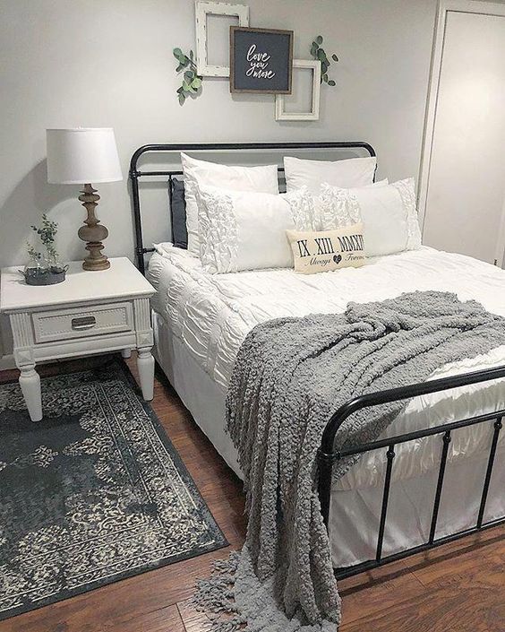 a bed with white sheets and pillows in a bedroom next to a rug on the floor