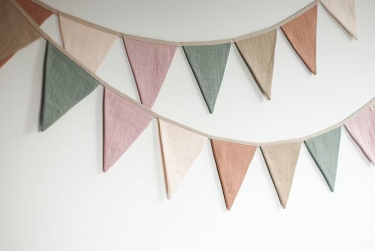 a group of multicolored flags hanging on a wall next to a white wall