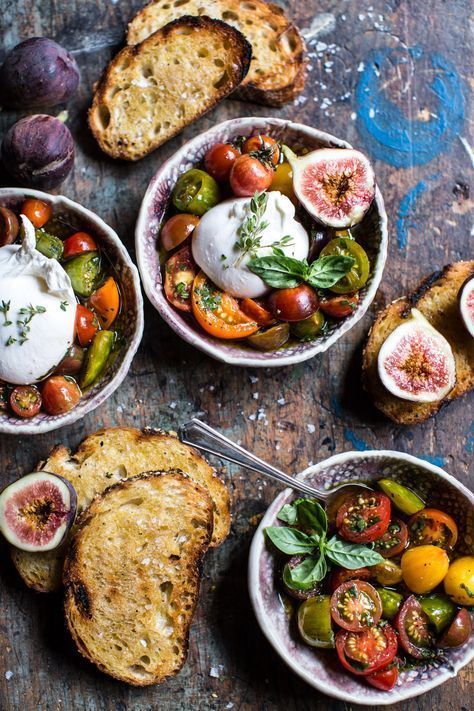 three bowls filled with different types of food on top of a wooden table next to bread