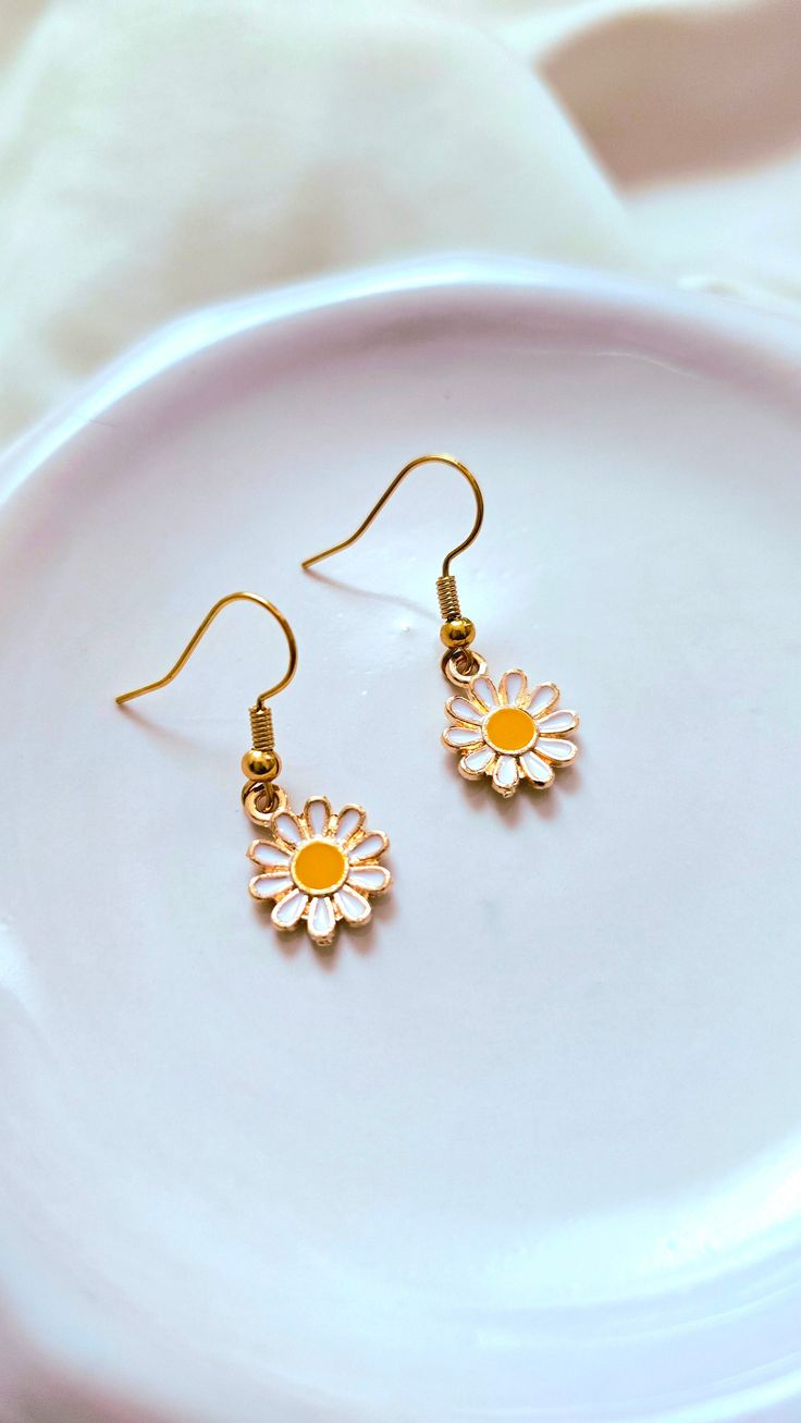 Add a touch of whimsy to your outfit with our Daisy Earrings. These adorable daisies will bring a smile to your face and brighten up any look. Perfect for adding a playful touch to your style. 🌼 Earring Details: White daisies Gold furnishings Everyday Daisy Earrings, Trendy Daisy-shaped Spring Jewelry, Trendy White Daisy-shaped Jewelry, Adjustable Yellow Daisy Jewelry, Dainty Daisy-shaped Earrings With Flower Charm, Daisy Earrings, Text Color, Apparel Accessories, Colorful Backgrounds