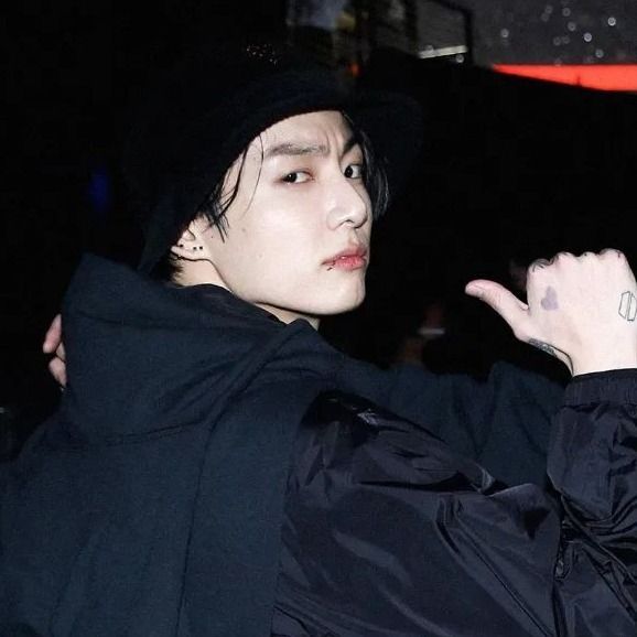 a young man in a black hoodie holding his hand up to the side and pointing at something