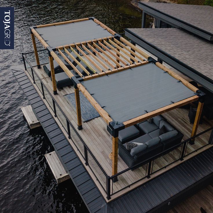 a boat dock with couches on the deck and water in the backround