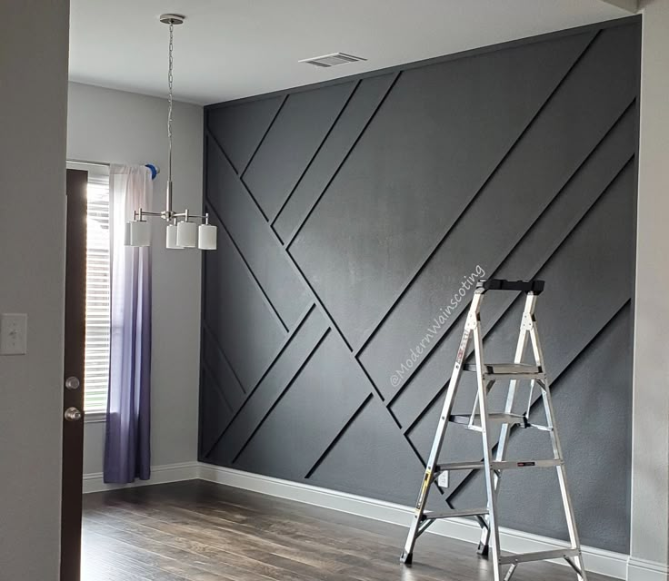 a ladder is standing in front of a wall painted with black and white geometric designs