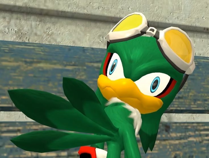 the green bird is wearing goggles and holding a red object in front of him