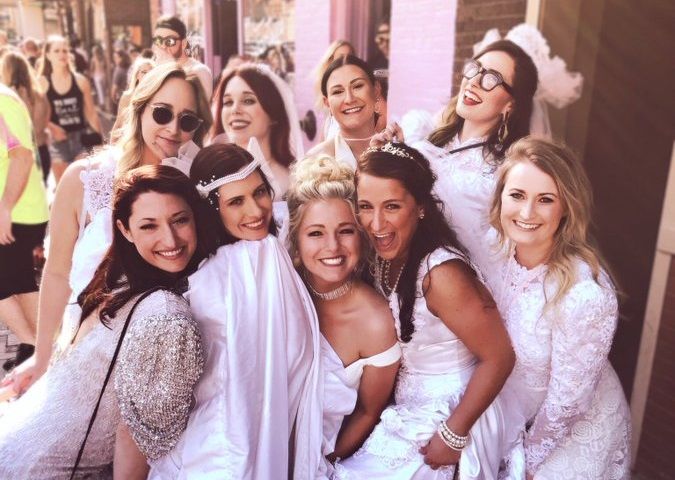 a group of women dressed in white posing for a photo with one woman wearing a costume