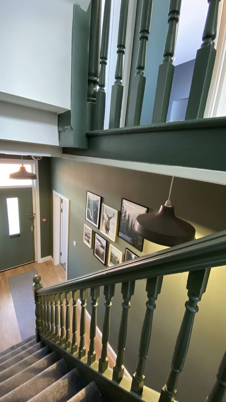 a staircase with pictures on the wall next to it and a lamp hanging from the ceiling