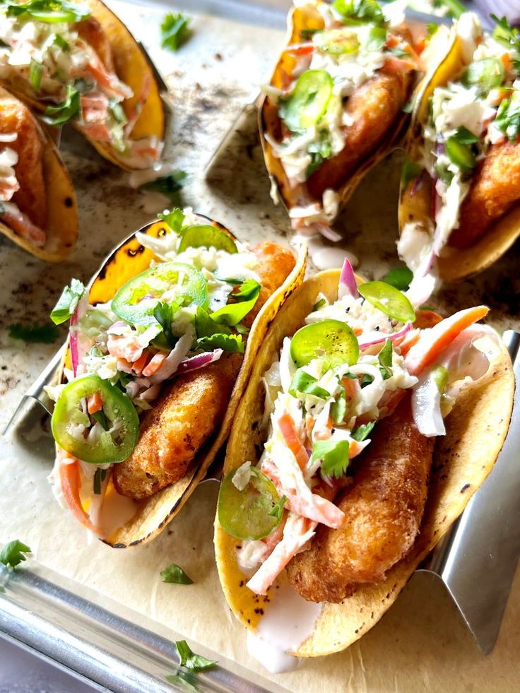 four fish tacos are sitting on a tray