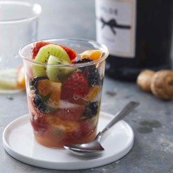 a glass filled with fruit on top of a white plate