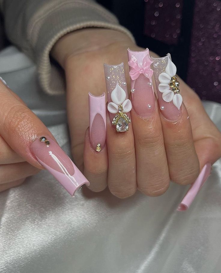 a woman's hands with pink and white nail polishes on them, decorated with flowers