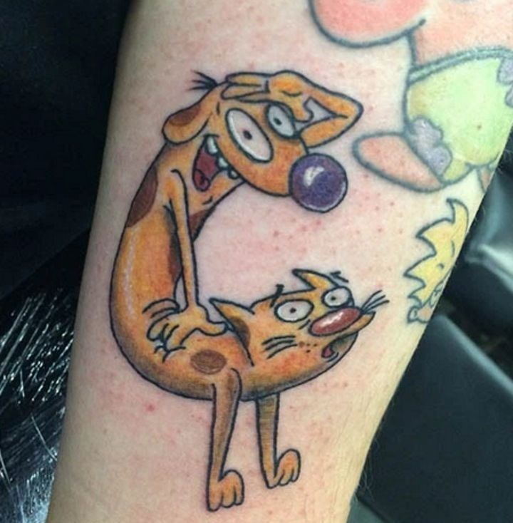 a cartoon cat and dog tattoo on the left arm, with an orange balloon in the air