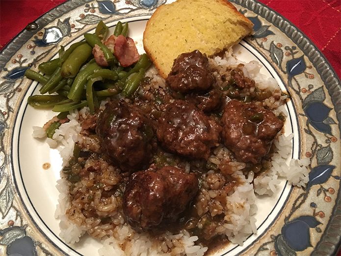 a plate with meatballs, rice and green beans on it next to a piece of bread