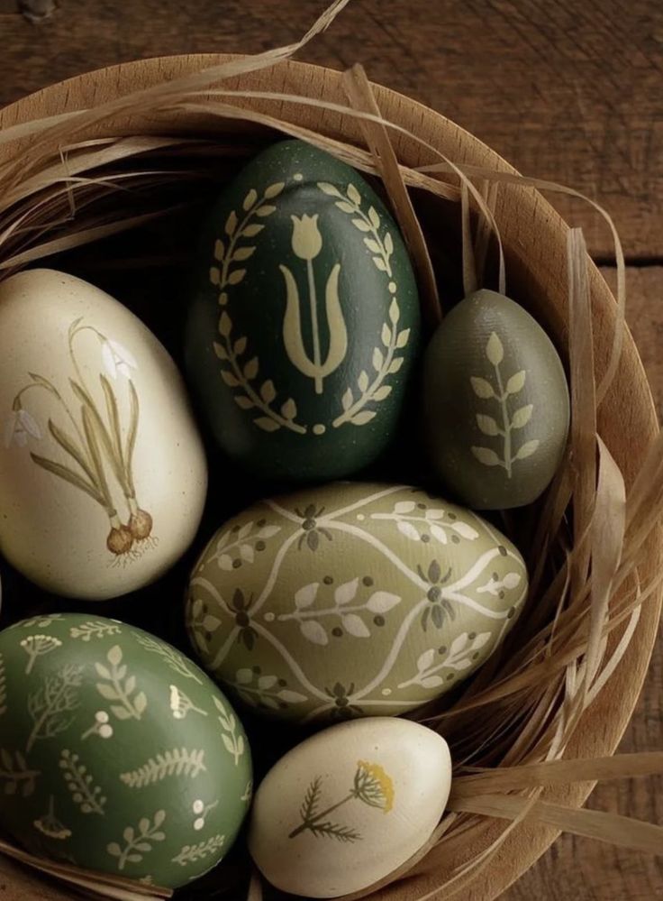 a basket filled with painted eggs on top of a wooden table