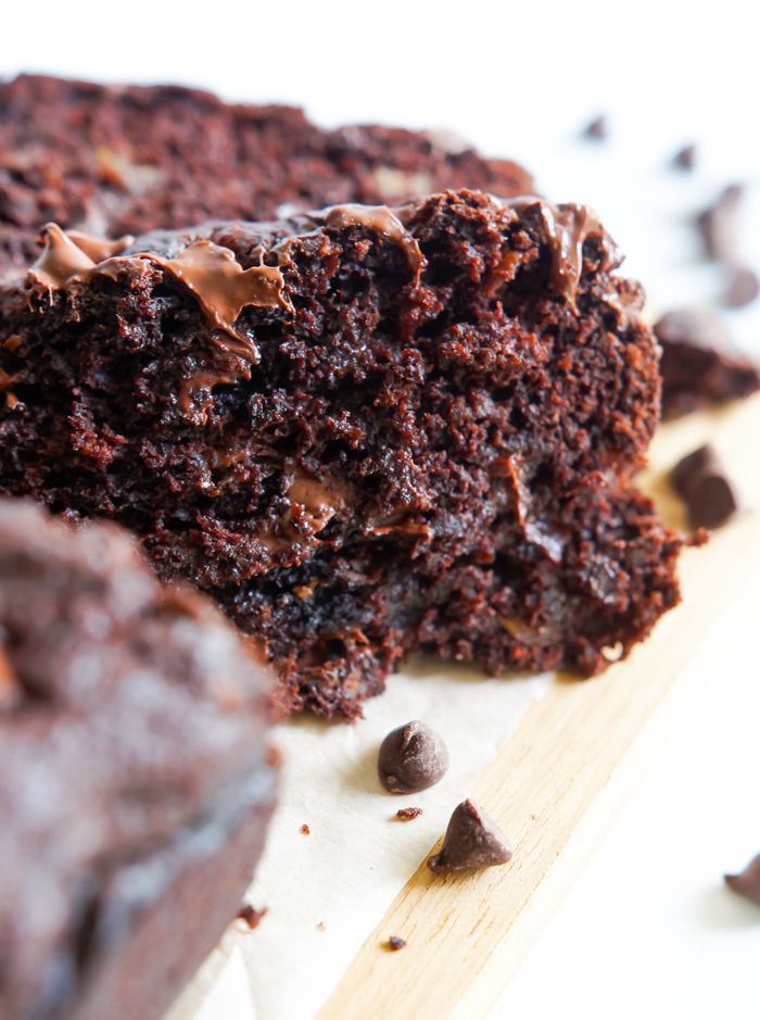 a close up of a piece of chocolate cake on a cutting board with one slice missing