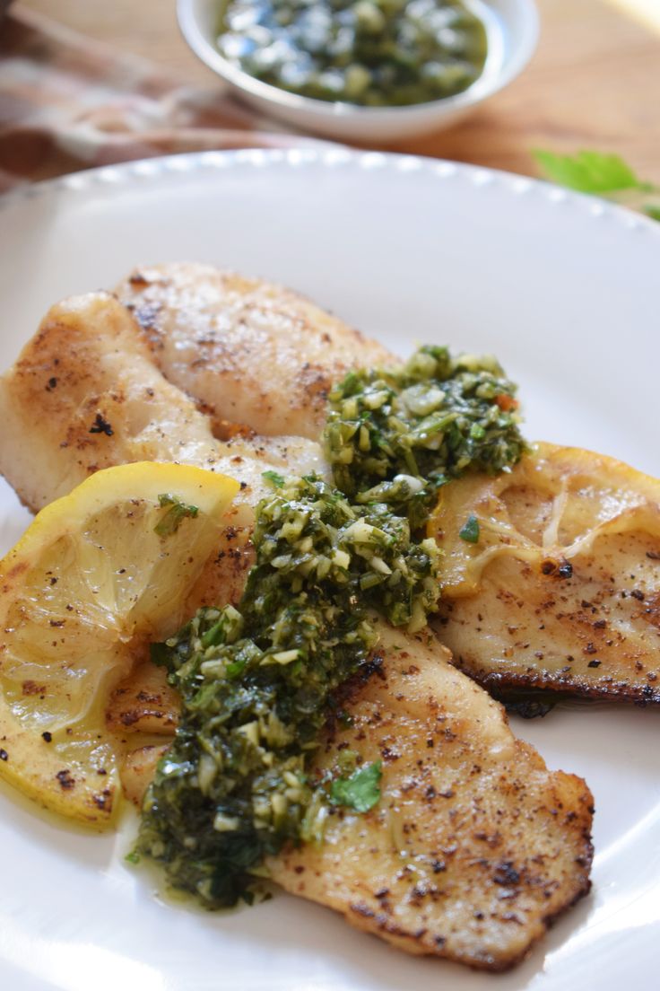 chicken with pesto and lemon slices on a white plate