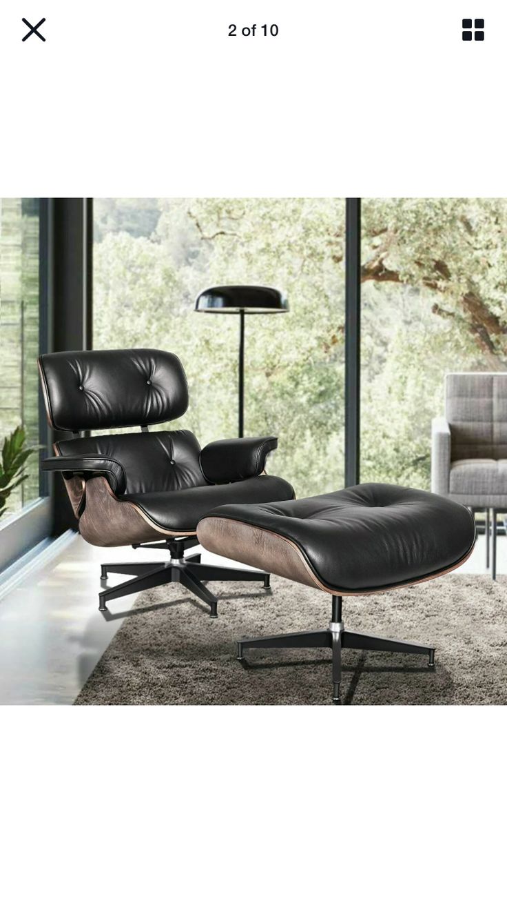 an eames chair and ottoman in front of a window